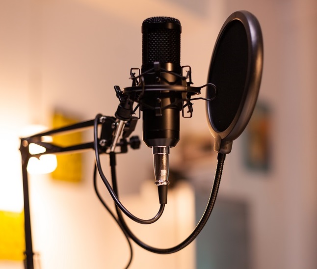 Zooming on professional microphone in vlogger home studio and neon light in the background. Influencer recording social media content with production microphone. Digital web internet streaming station